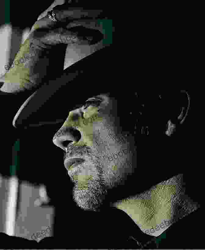 A Stoic Raylan Givens, Portrayed By Actor Tim Olyphant, Stands In A Dimly Lit Setting, Clutching A Gun In His Right Hand And A Cigarette In His Left. His Piercing Gaze Conveys A Mix Of Determination And Weariness. Fire In The Hole: Stories (Raylan Givens 4)